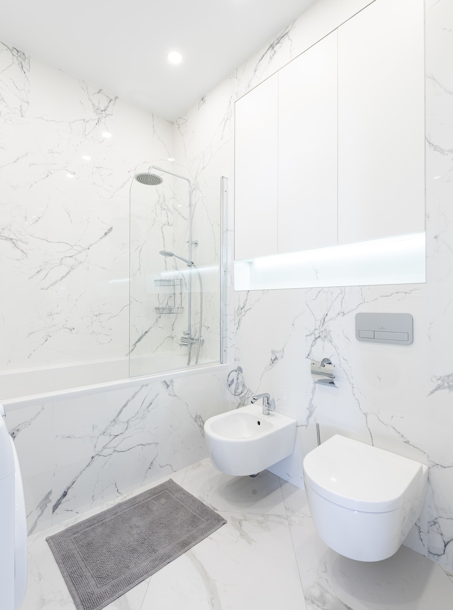 Bathroom interior with bidet and toilet near bath