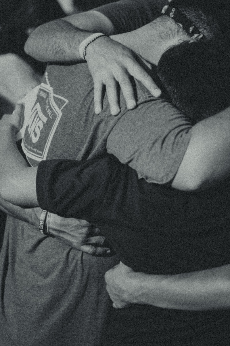 grayscale photography of men doing group hug