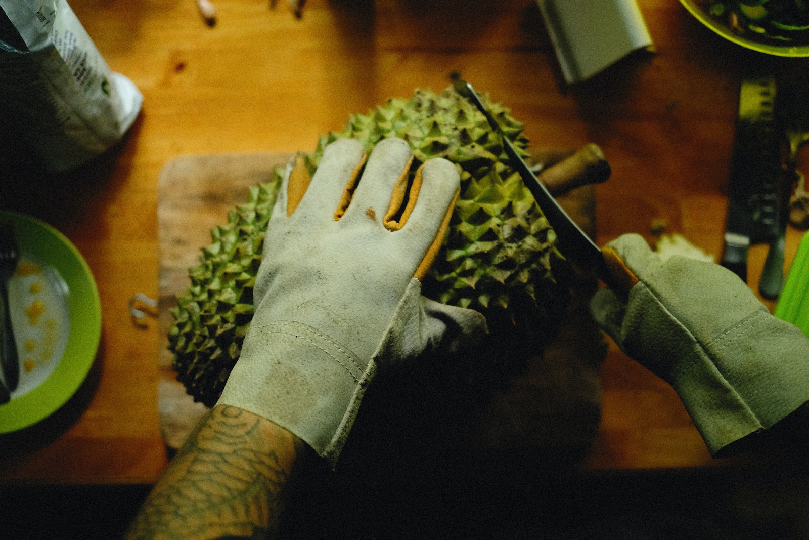a person cutting a durian fruit on a cutting board