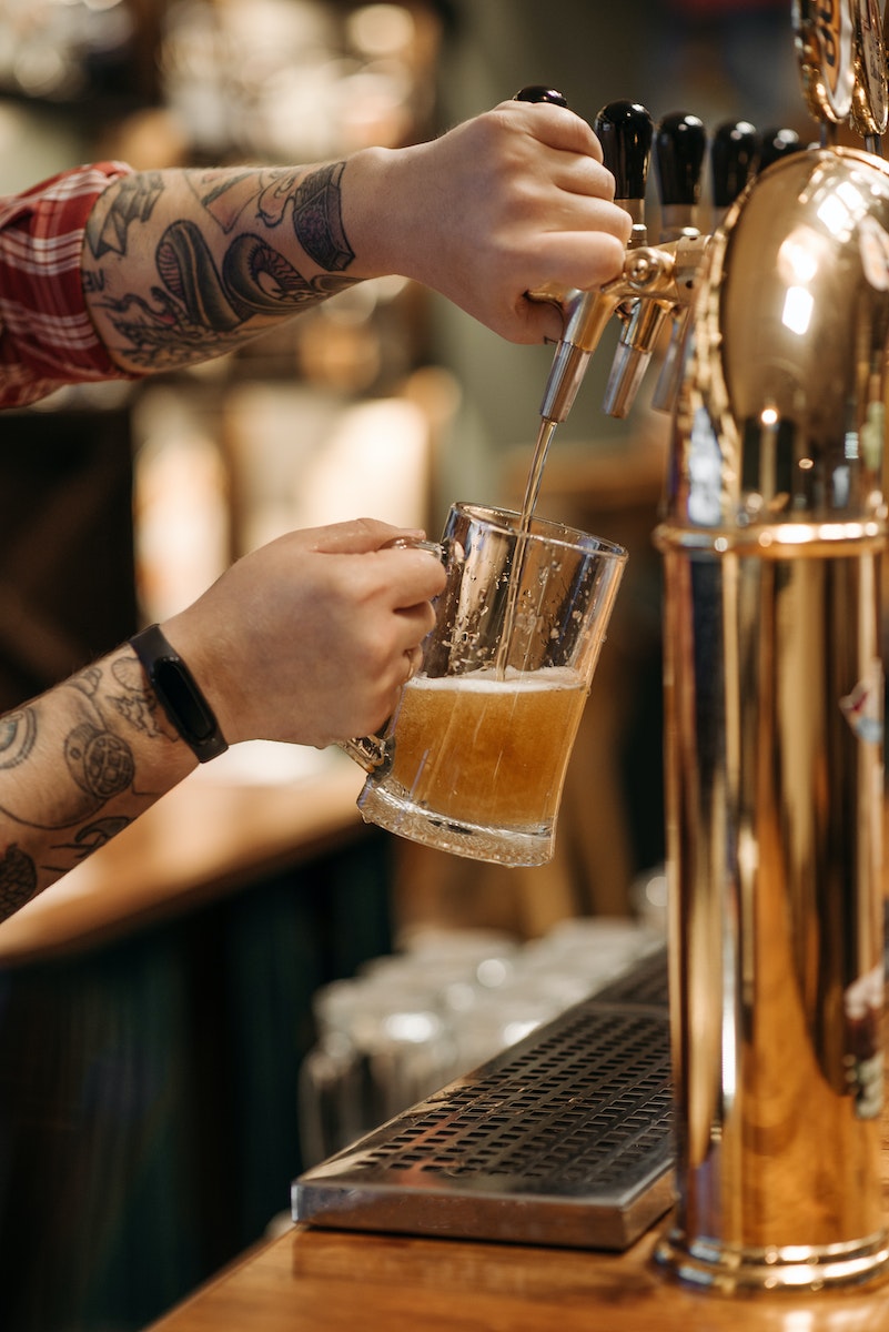 Person Pouring Brown Liquid on Clear Drinking Glass