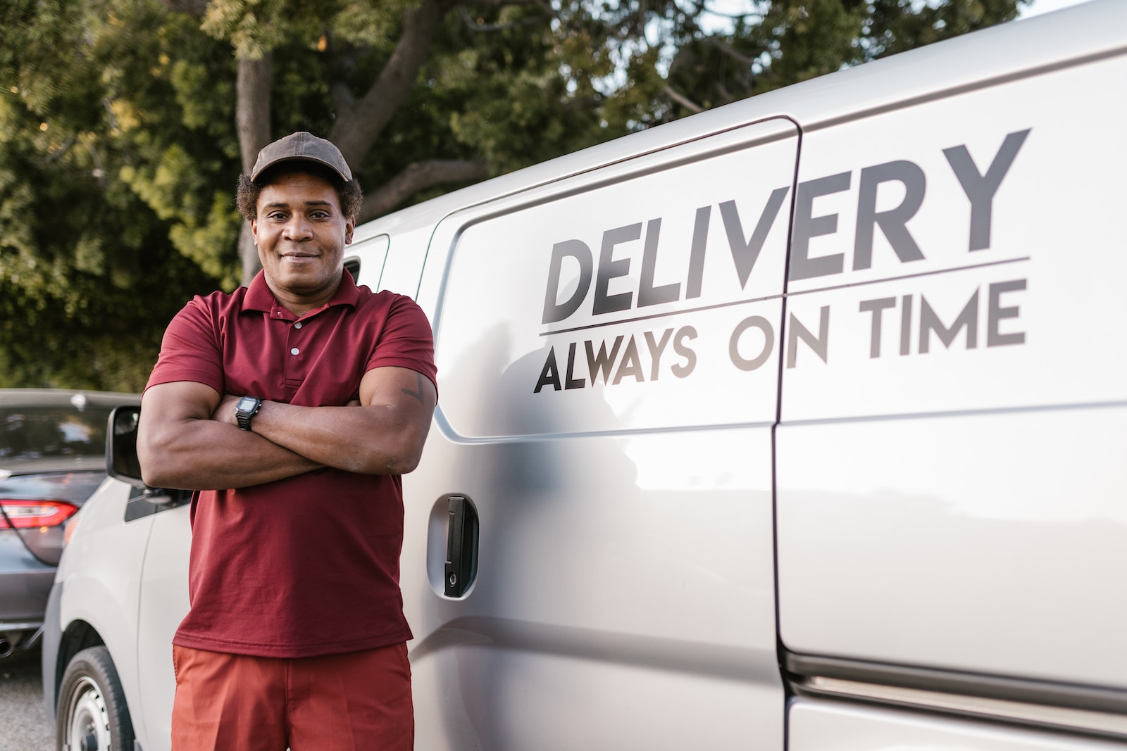 Man in Red and Black Polo Shirt Standing Beside White Van