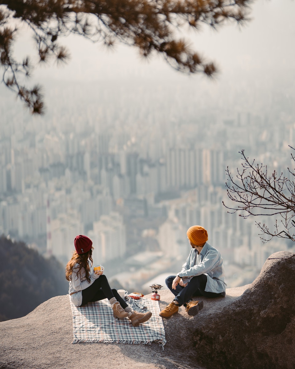 A Couple Sitting on Cliff Having a Picnic