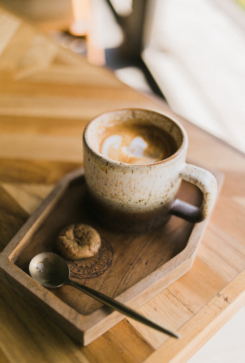 Spoon with cookie by cup of coffee