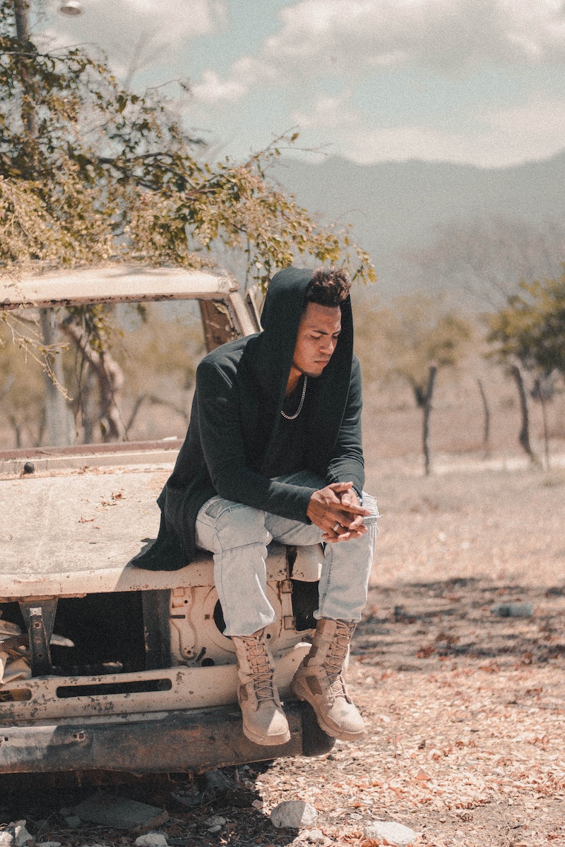 Man Sitting On Broken Vehicle