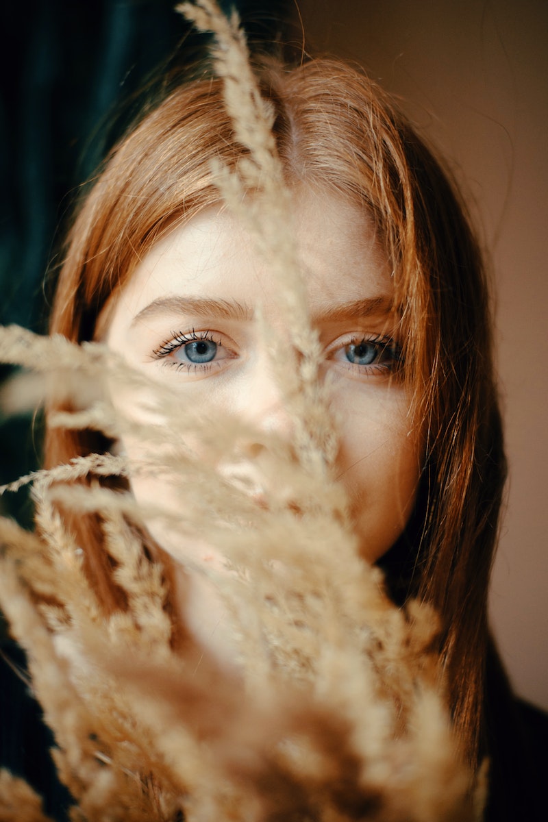 Selective Focus Photography of Woman Hiding Behind Flowers