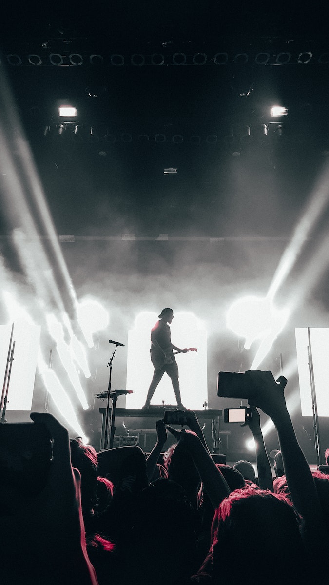 Crowd of People Watching a Man Perform on Stage