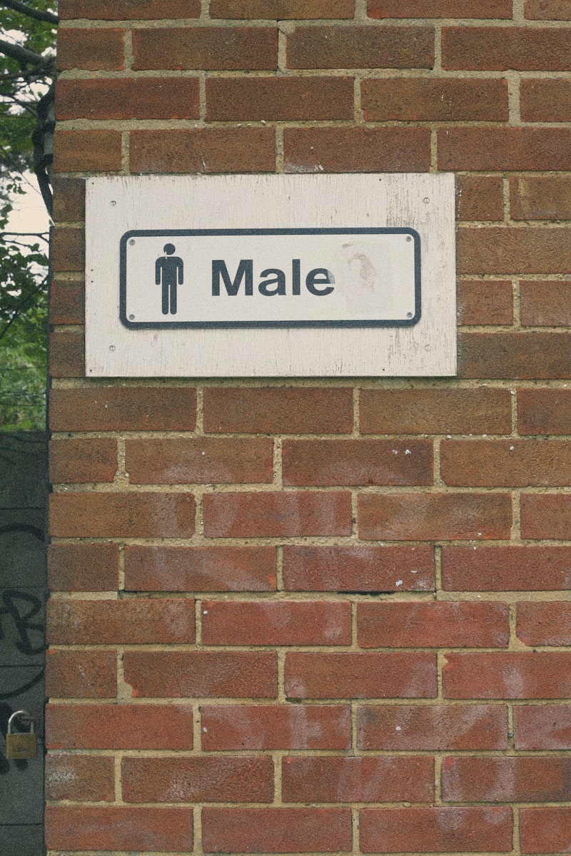 A Male Restroom Sign on Brick Wall