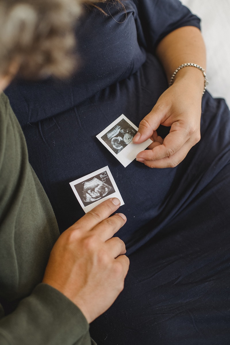 Unrecognizable pregnant couple with sonogram images in hands