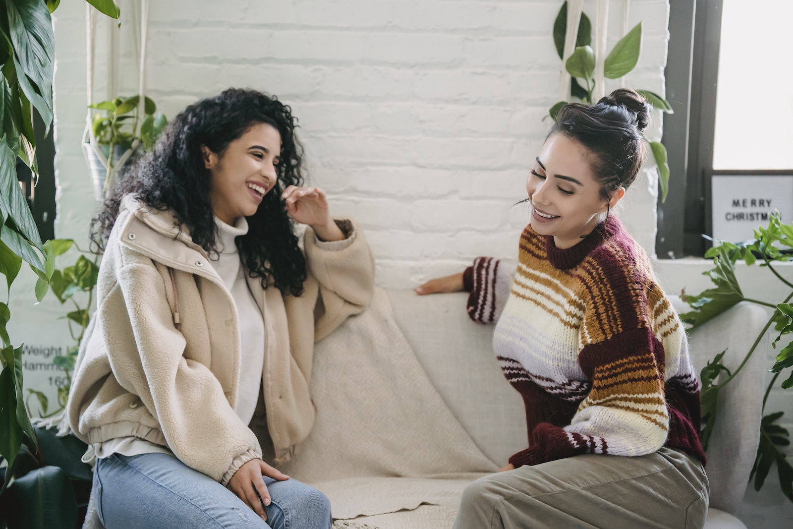 Side view of young woman in casual clothes sitting on sofa and talking while spending weekend together