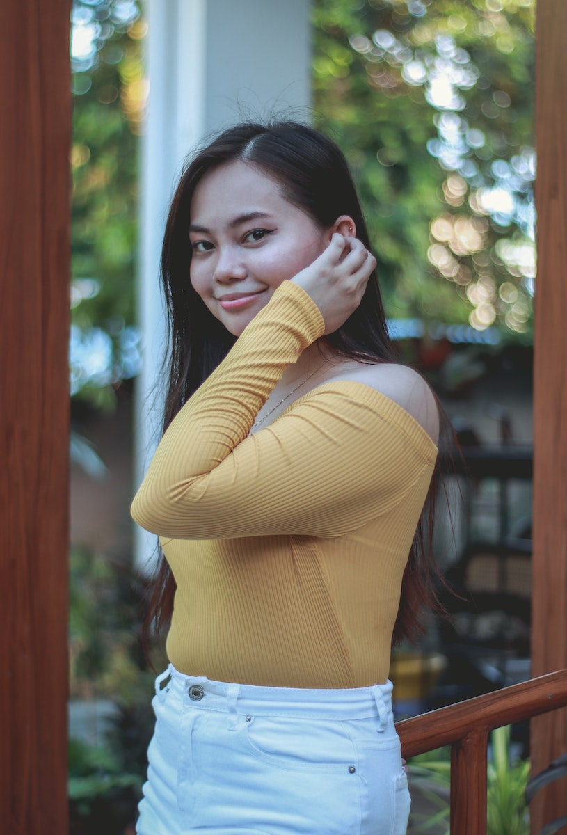 Young Woman Smiling and Tucking Her Hair Behind Her Ear