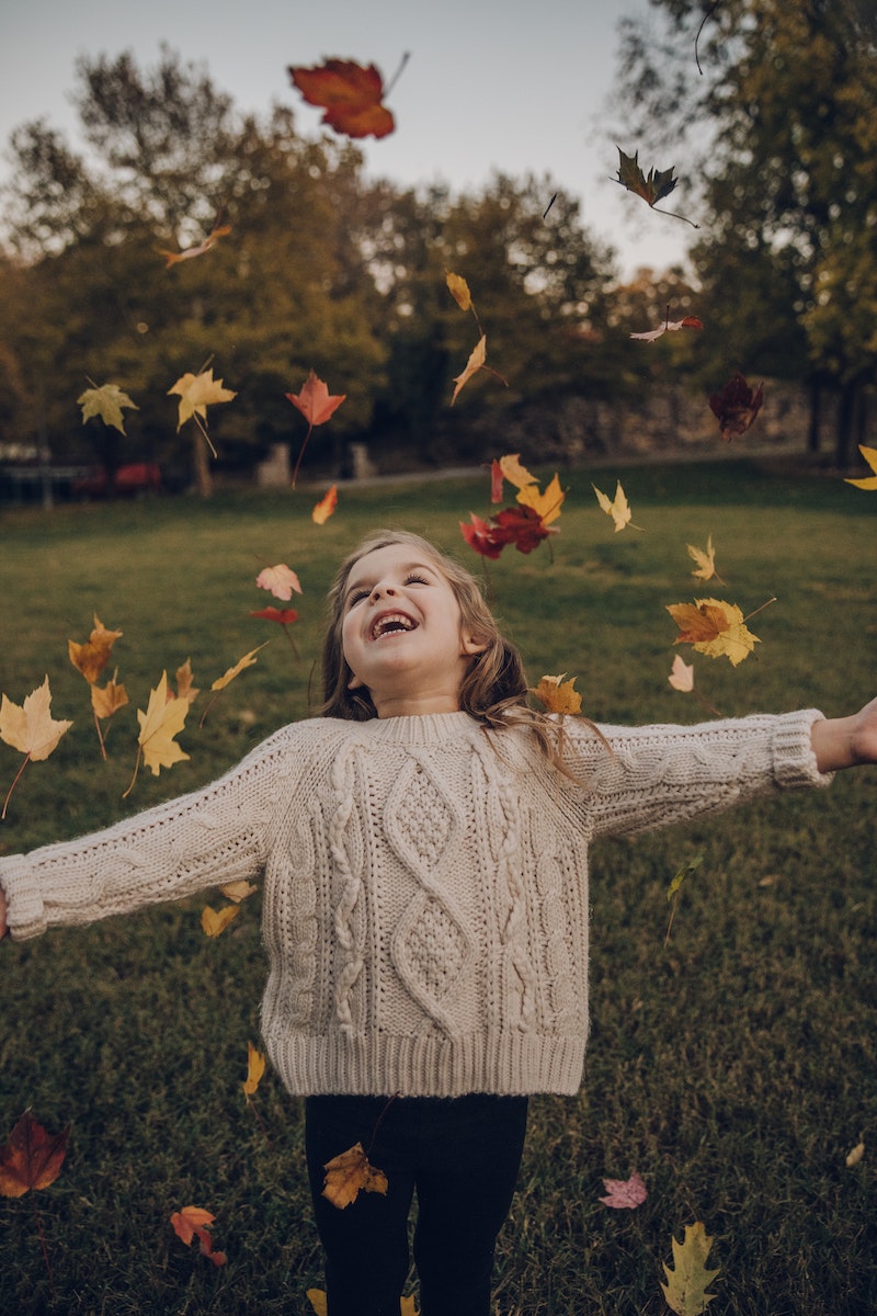 Girl Wearing Knitted Sweater Standing Outside With Leaves Falling