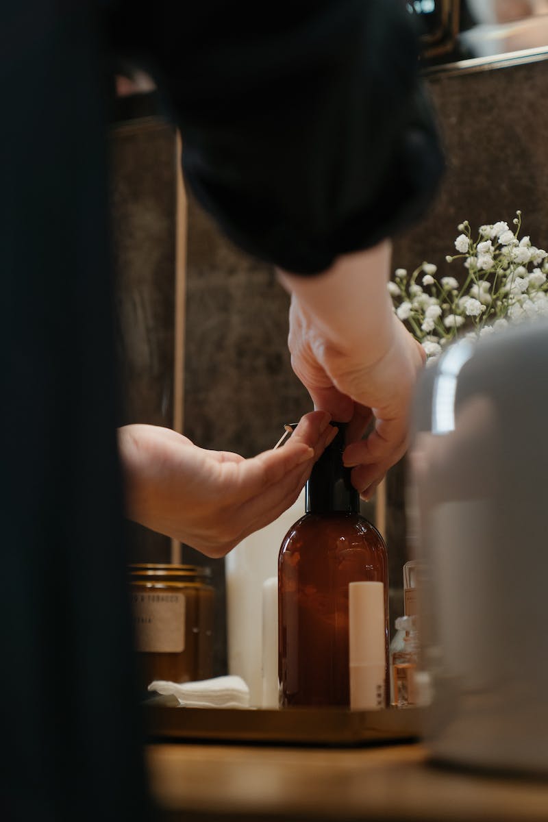 Person Holding Brown Glass Bottle