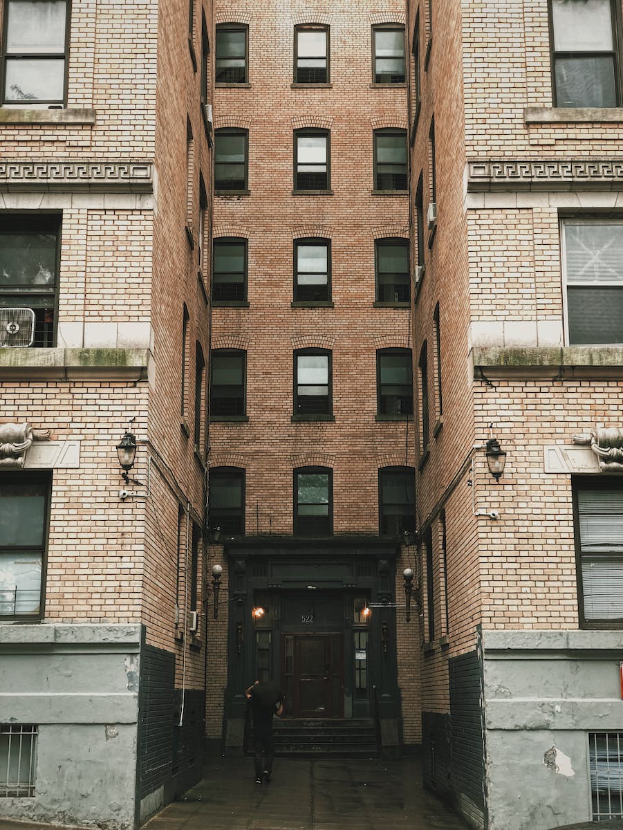 Person Standing Between Brown Concrete Building