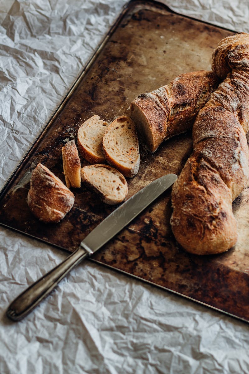 Stainless Steel Bread With Slices of Bread on Chopping Board