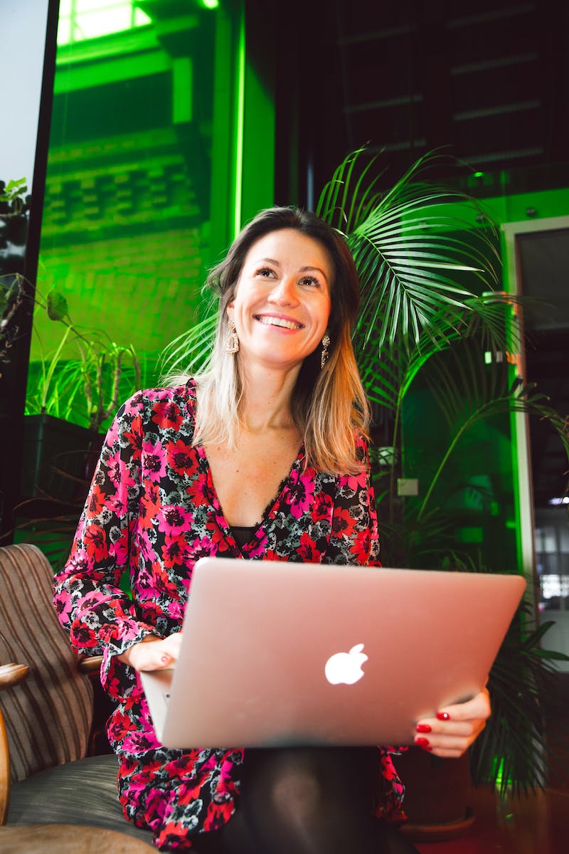 Woman in Red and Black Floral Dress Using Macbook