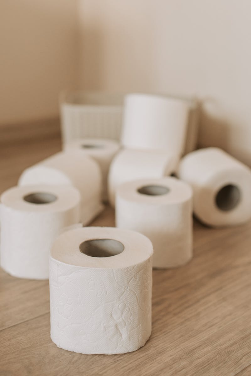 Set of white toilet paper tubes and plastic basket on bathroom floor