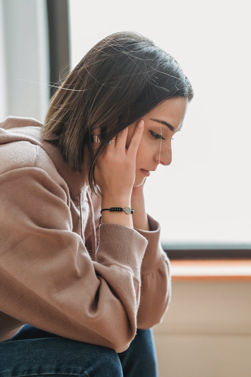 Sad woman with hands on head in room