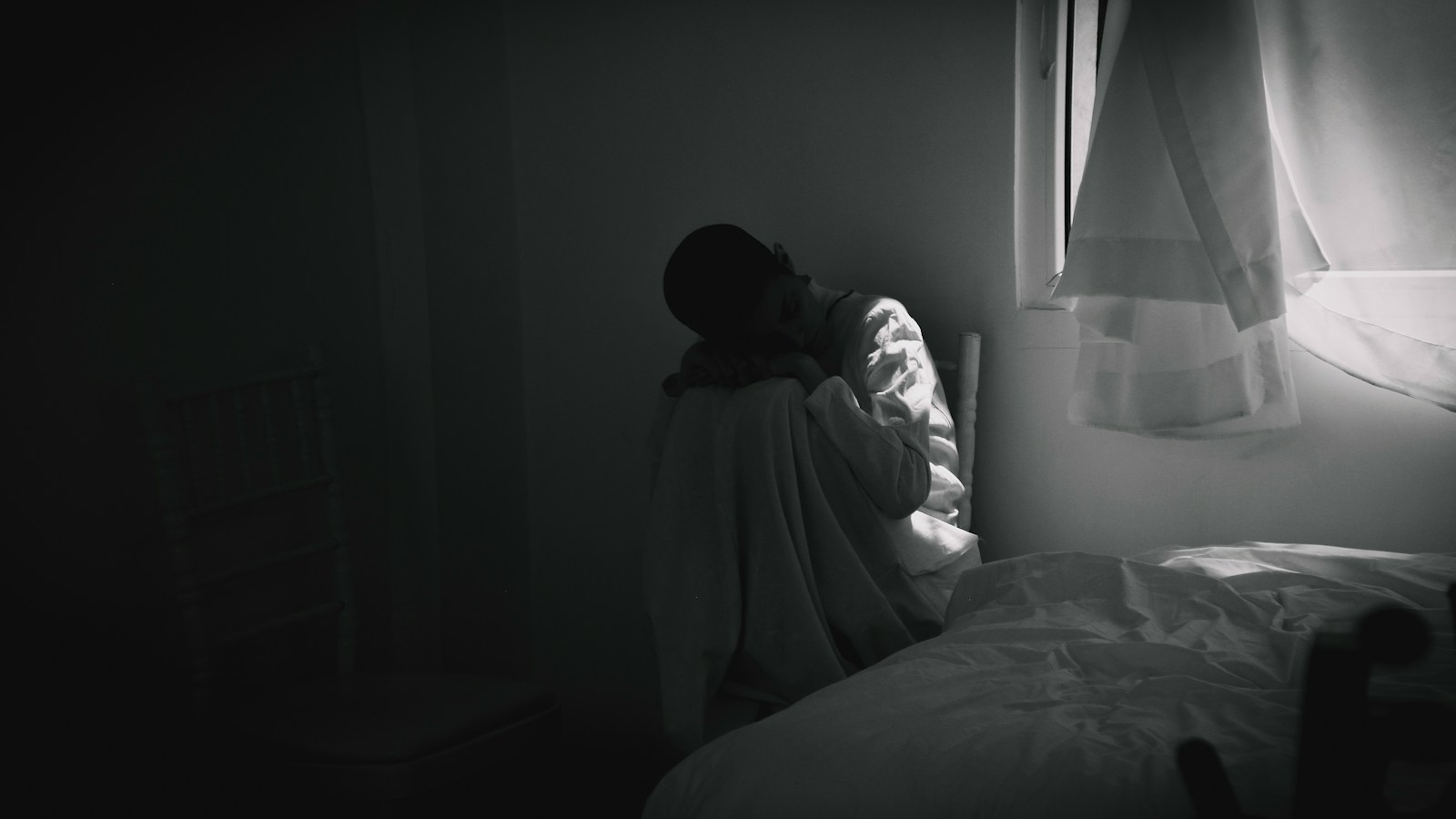 person in gray hoodie sitting on bed