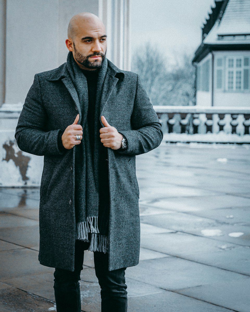 man in black coat standing on sidewalk during daytime