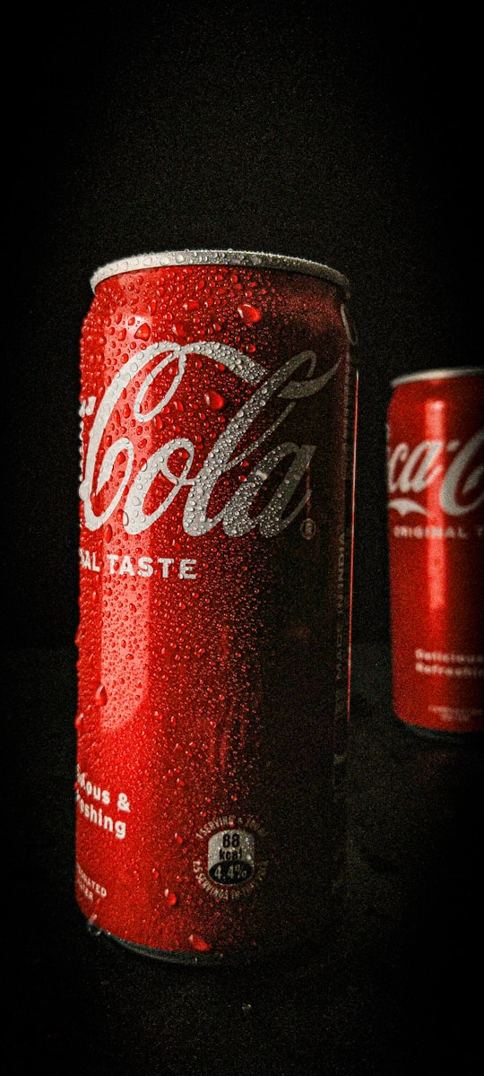 a can of coca cola next to a can of soda