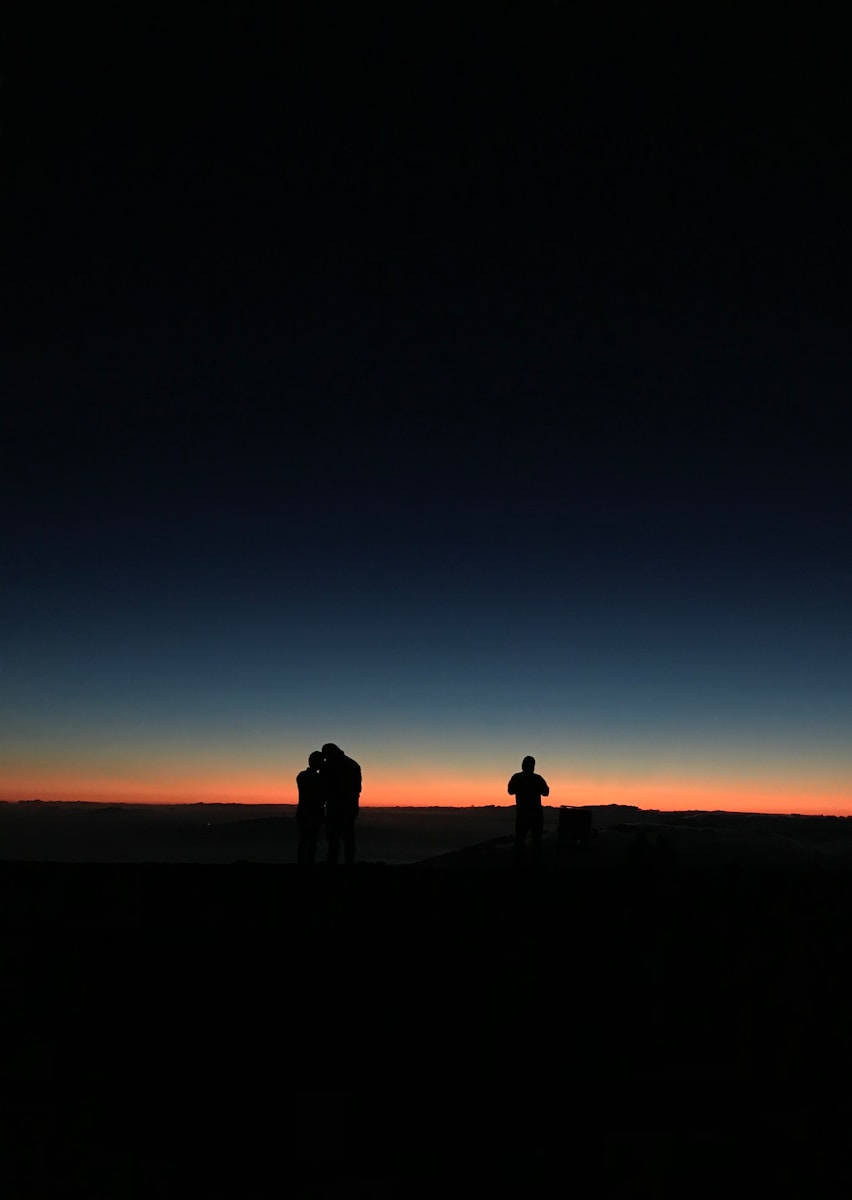 silhouette of 3 people at sunset