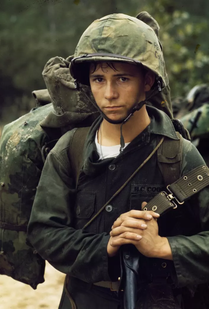 Mladý vojak v uniforme a prilbe sťažka nesie svoj batoh, pripravuje sa na nasledujúcu misiu.