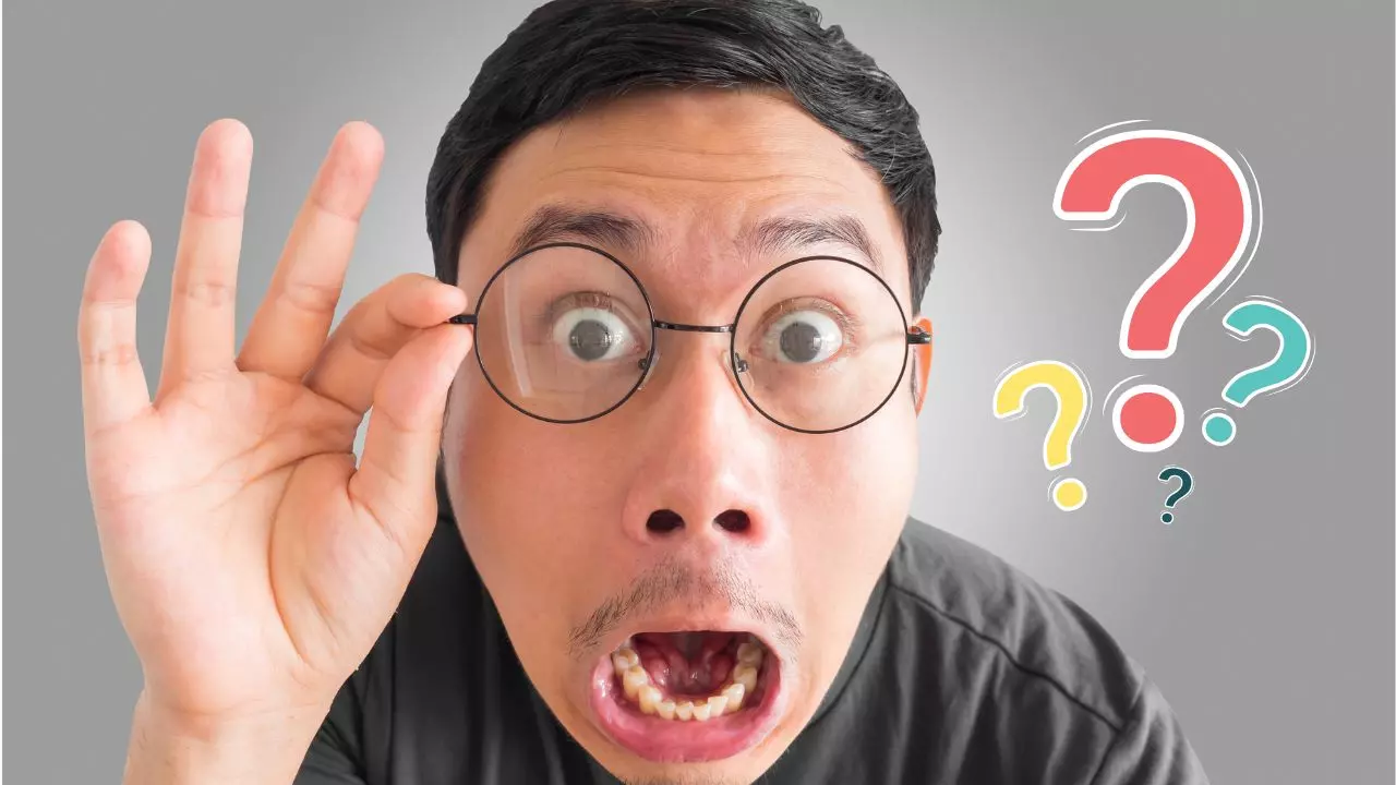 Muž s okuliarmi vyjadruje prekvapenie, okolo neho sú pestrofarebné otázniky na šedom pozadí.