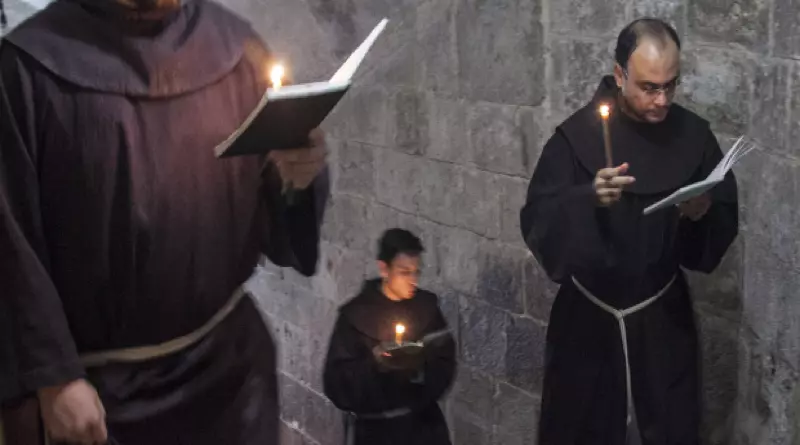 Mnísi kráčajú po schodoch so sviečkami a čítajú modlitebné knihy v kláštornom prostredí.