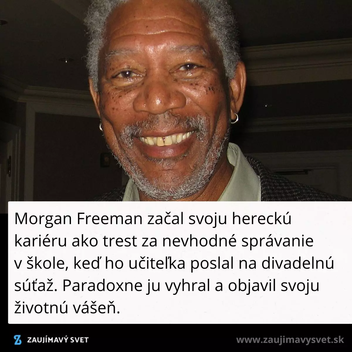Neznámy muž s úsmevom na tvári, oblečený v saku a košeli, v interiéri osvetlenom tlmeným svetlom.