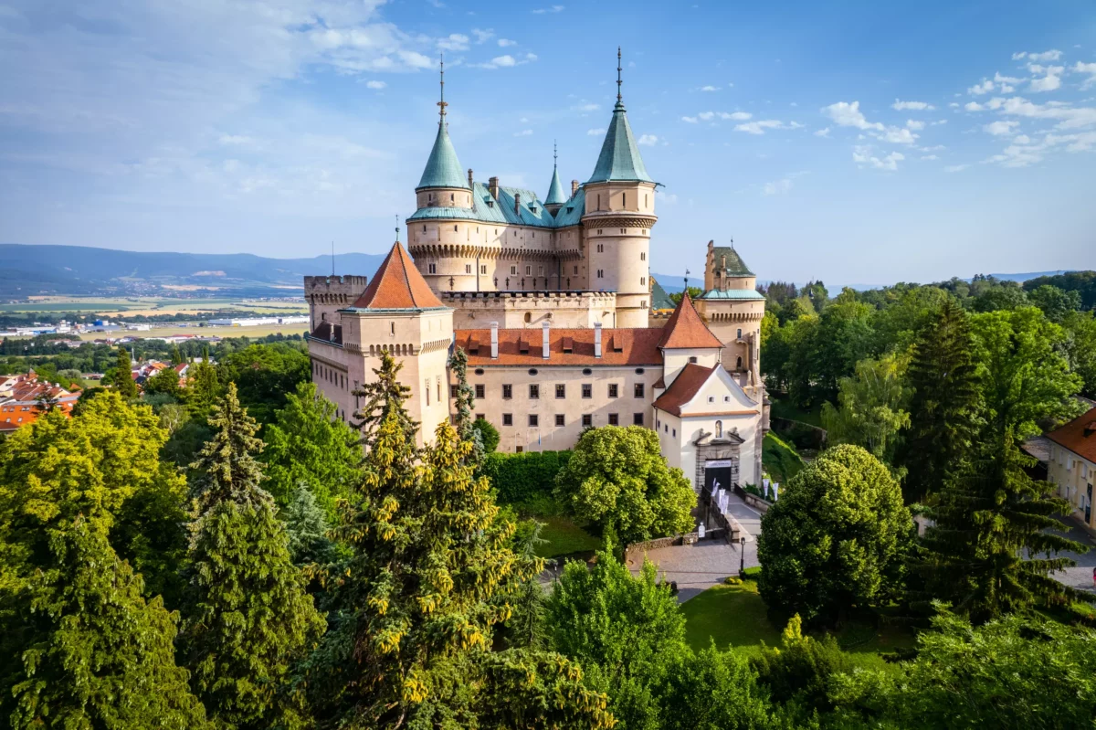 Bojnický zámok v lete obklopený zeleňou a modrou oblohou, jeden z najznámejších hradov na Slovensku.