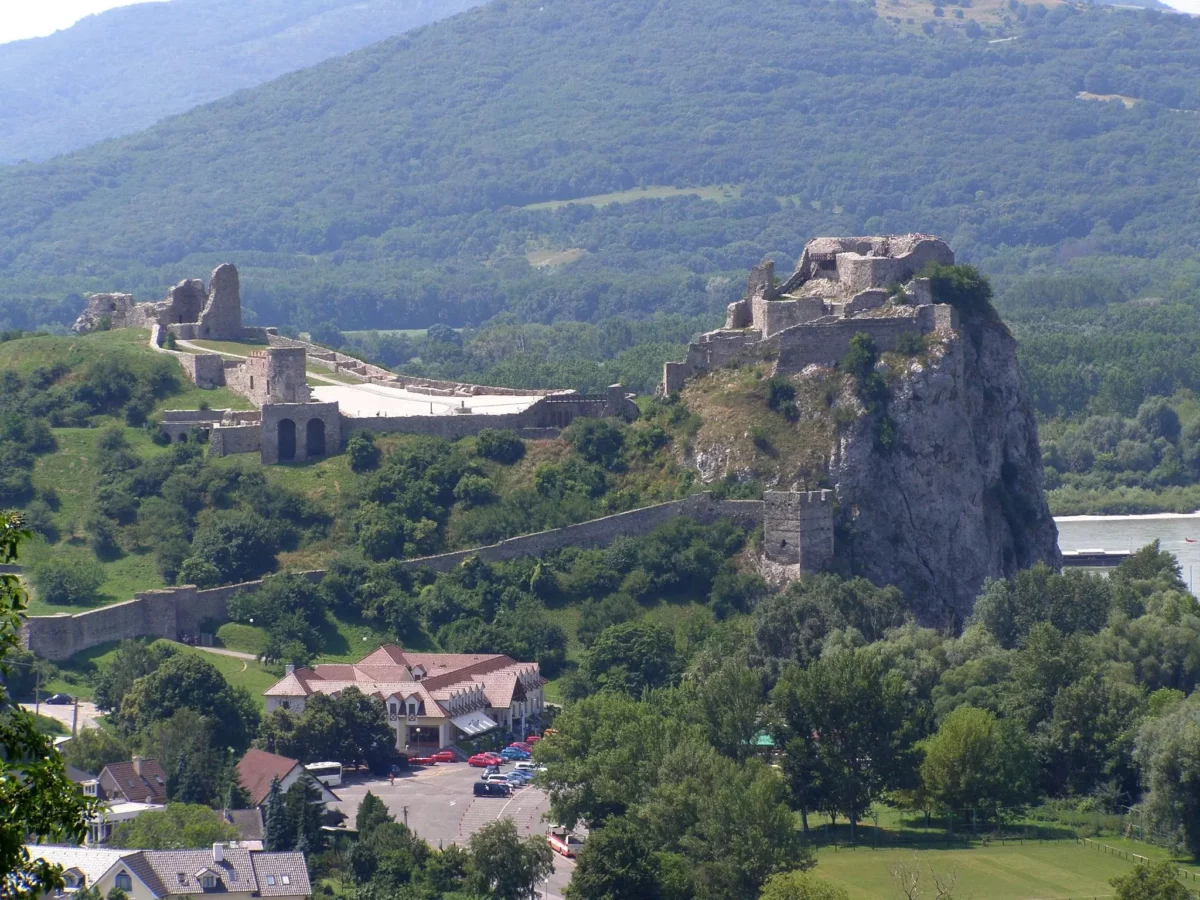 Hrad Devín na vrchu pri rieke, obklopený zeleňou a kopcami, historická pamiatka Slovenska.