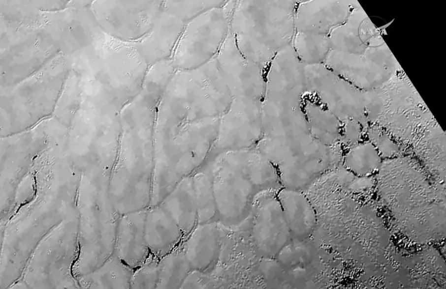 Povrch Pluta s detailnými planinami a trhlinami, zachytený zblízka vesmírnou sondou New Horizons.