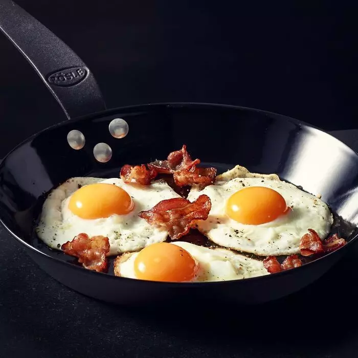 Smažené vajcia a opečená slanina na panvici, ideálne raňajky pre chuťový zážitok.