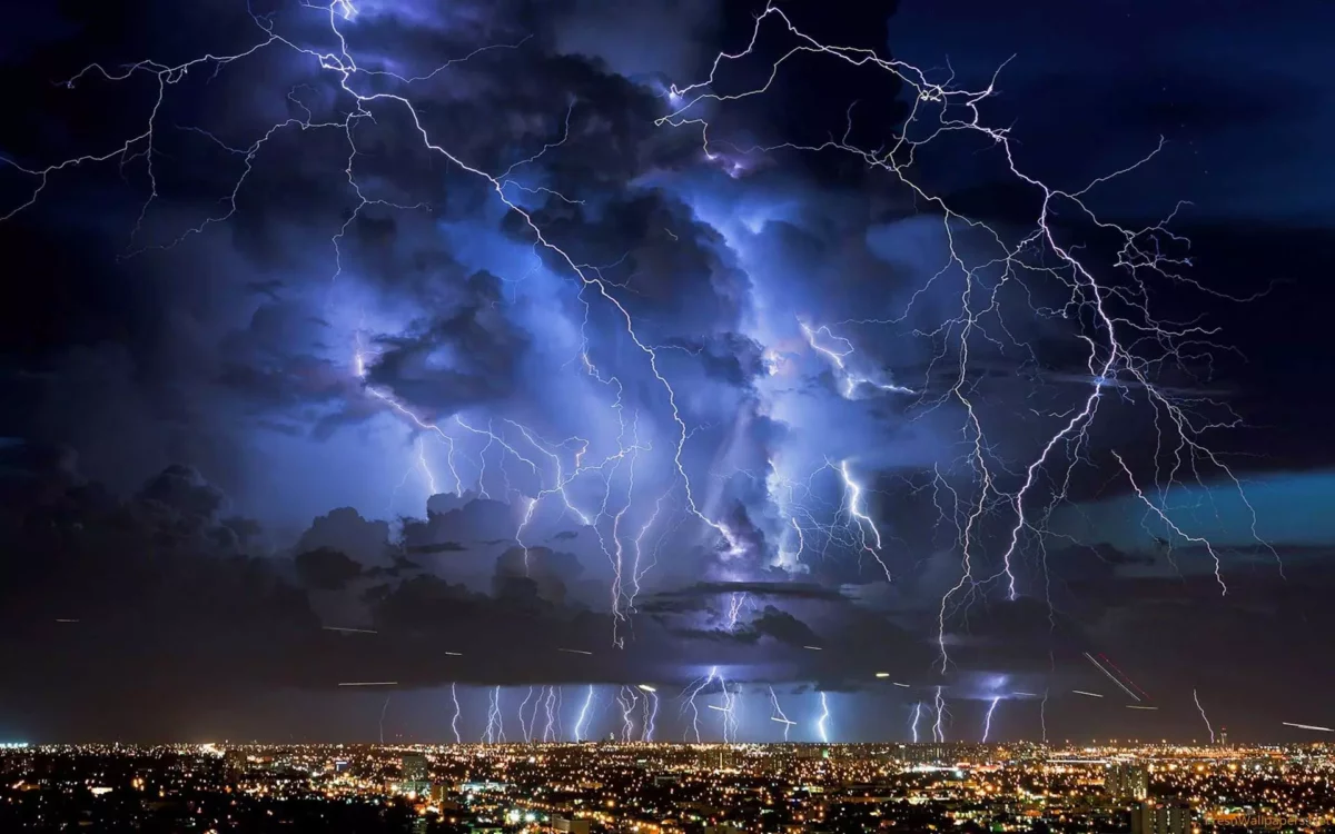Mesto pod nočnou búrkou; dramatické blesky osvetľujú oblohu nad rozsvietenou panorámou.
