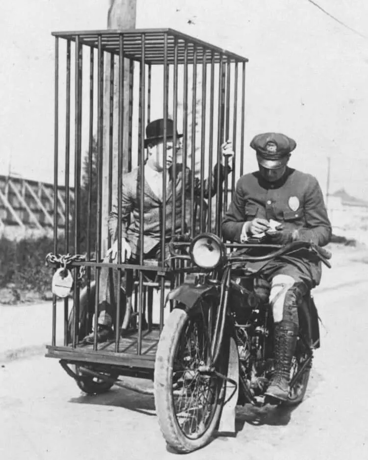 Policajt na motocykli s väzňom v klietke, historická fotografia z minulého storočia.