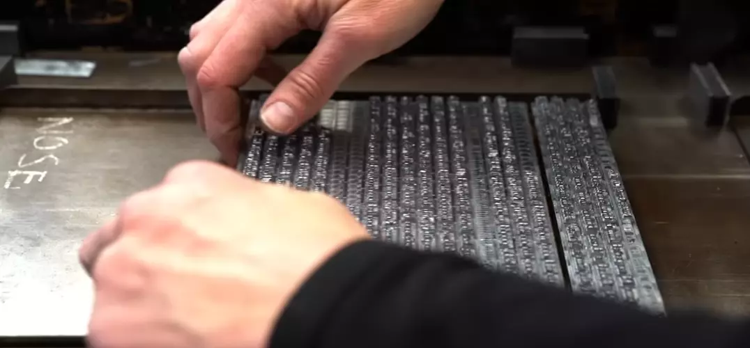 Ruči prípravujú kovové písmená na tlač v typografickej dielni.