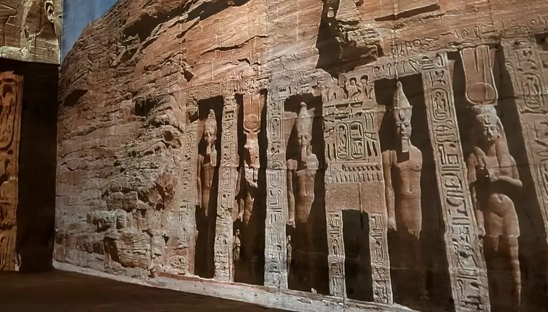 Staroveký skalný chrám s vytesanými sochami v Egypte, bohato zdobený hieroglyfmi.