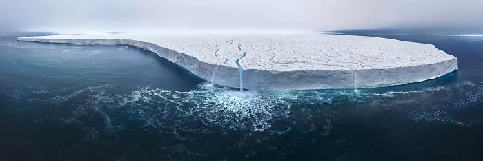 Ľadová kryha s prasklinou ústiacou do oceánu, znázorňujúca topenie ľadovcov a klimatické zmeny.
