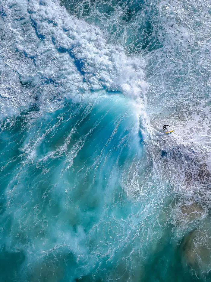 Surfer jazdiaci na veľkej vlne v tyrkysovom oceáne, pohľad z výšky.