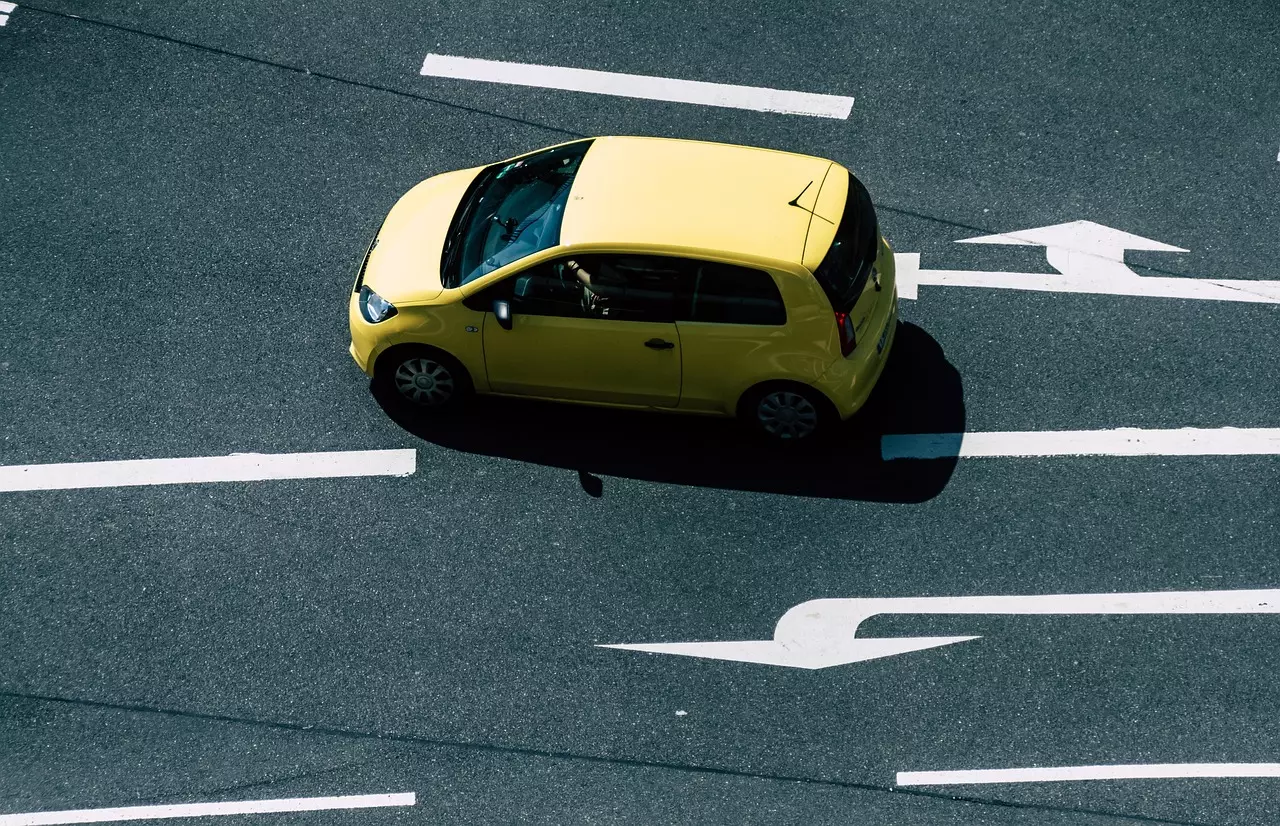 Žlté auto na mestských cestách zapnutých smerových šípok, pohľad zhora.
