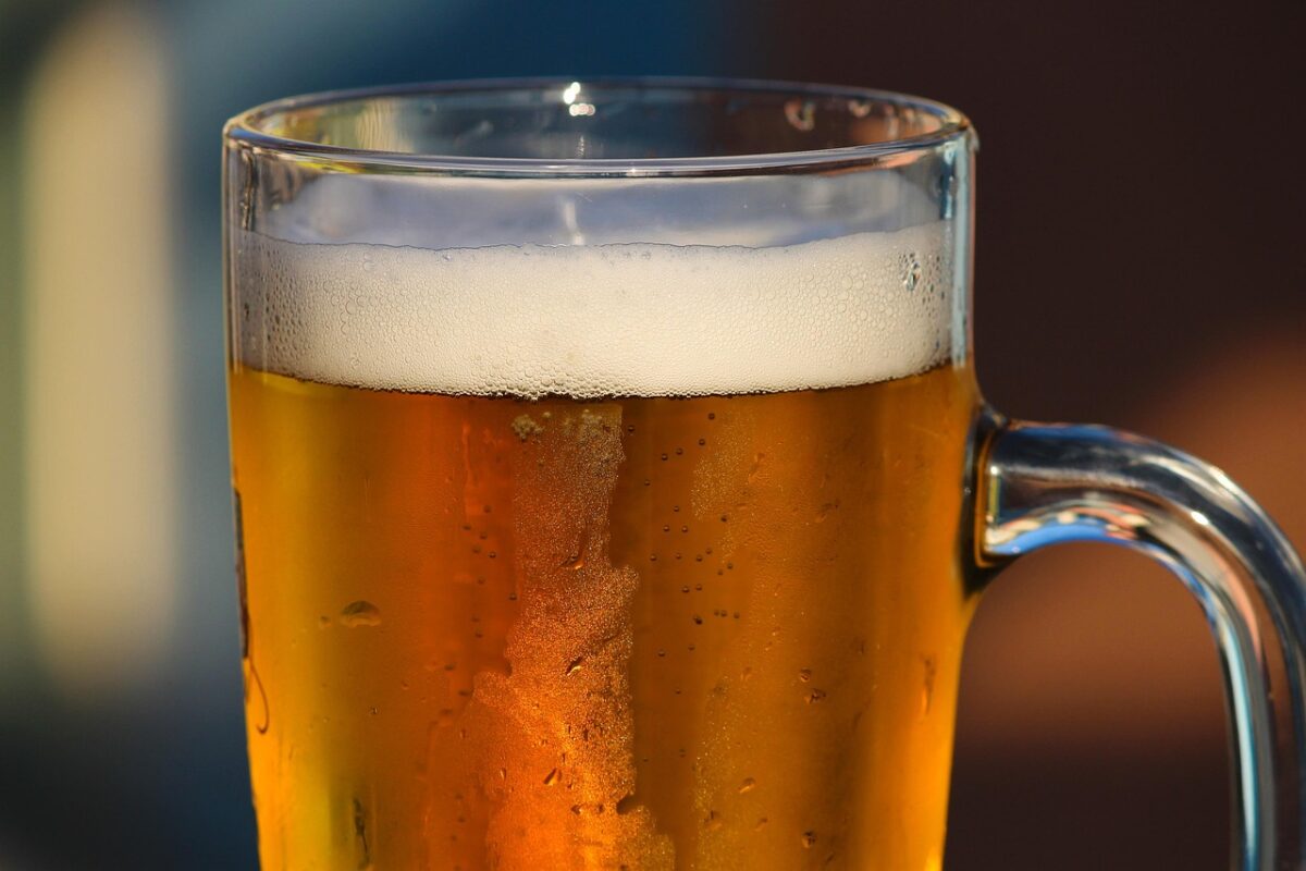 Pohár zlatistého piva s hustou penou v osviežujúcom svetle, ideálny pre relax na terase.