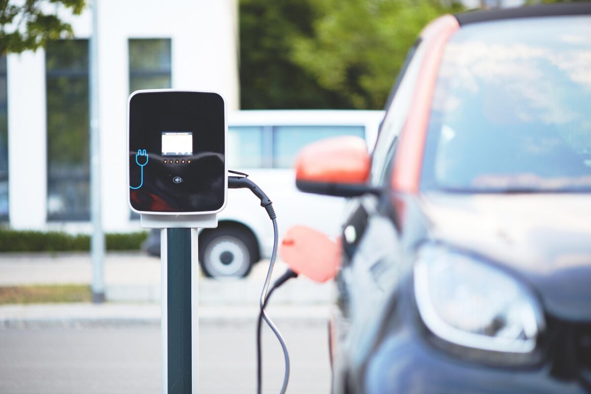 Nabíjacia stanica pre elektromobily s pripojeným autom na ulici. Zelená doprava a moderná technológia.