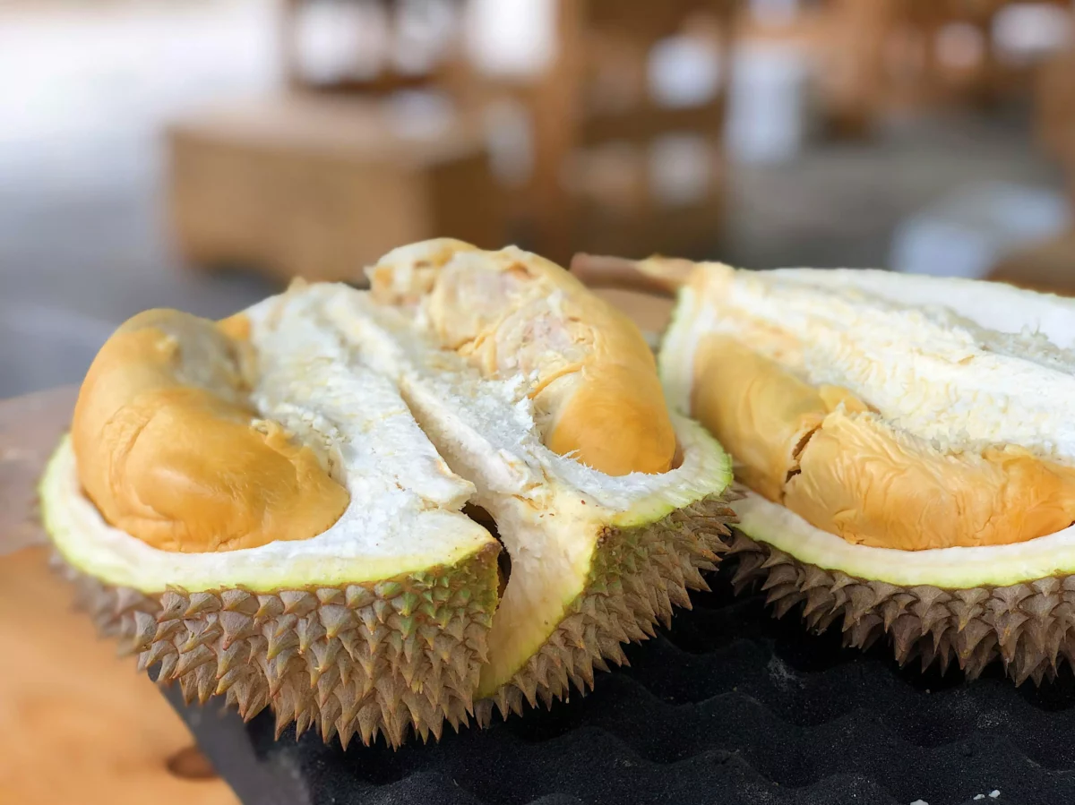Ostrý a žltý durian na stole, rozrezaný na polovicu s viditeľnou textúrou a charakteristickou šupkou.