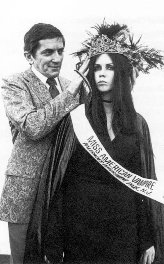 Pásková Miss American Vampire dostáva korunu od muža v obleku, čiernobiela retro fotografia.