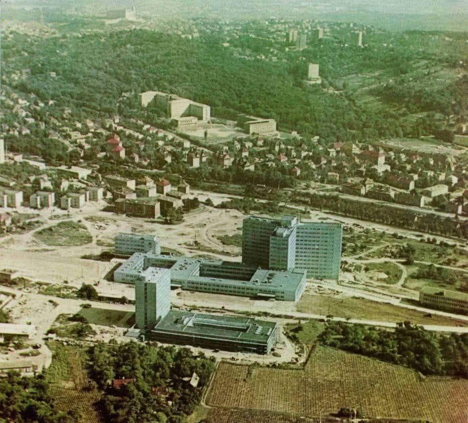 Letecký pohľad na mesto s modernou výstavbou, rozsiahlymi zalesnenými oblasťami a obytnými domami.
