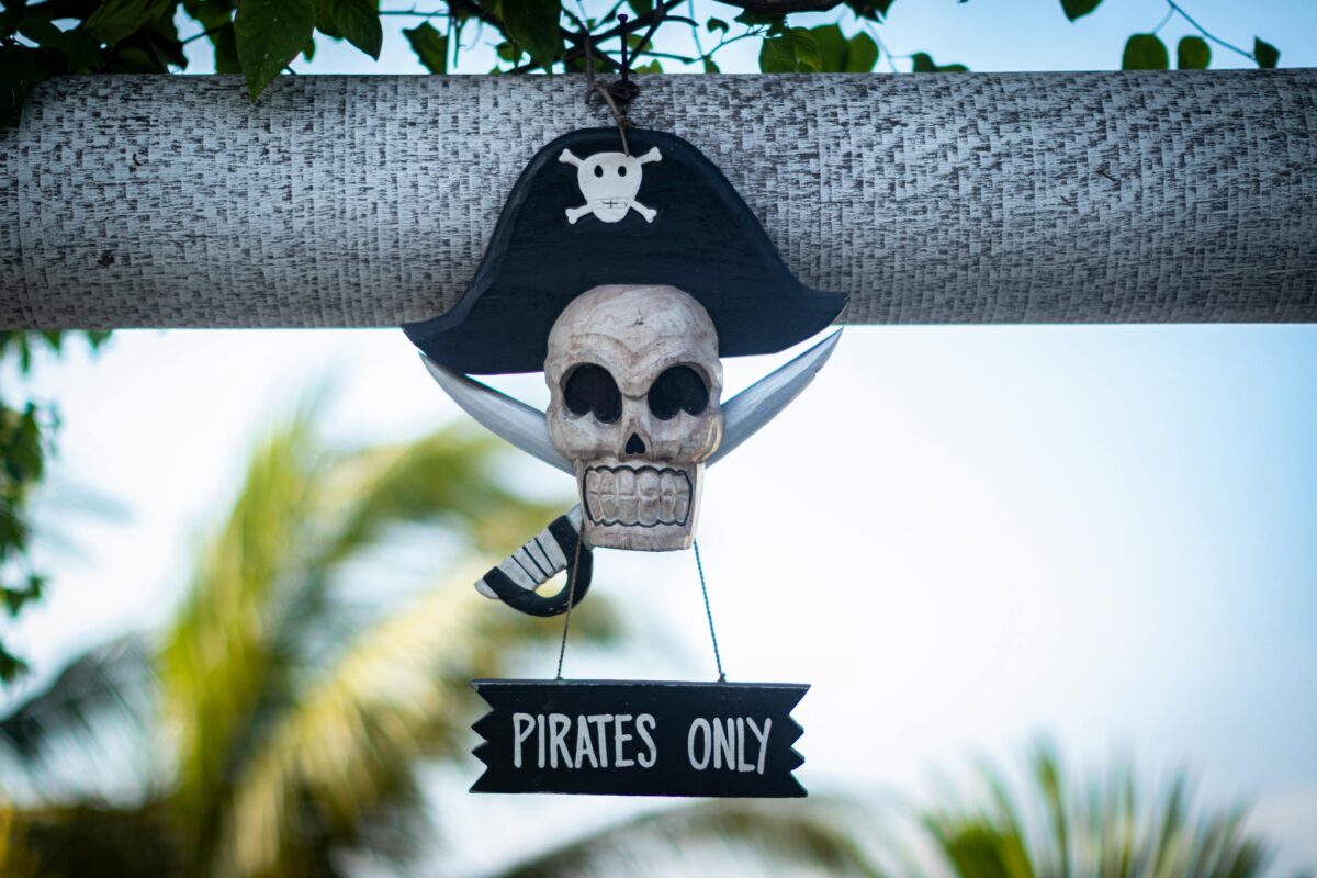 Pirátsky lebkový nápis Pirates Only zavesený na konári stromu, symbolizujúci výhradne pirátsku zónu.
