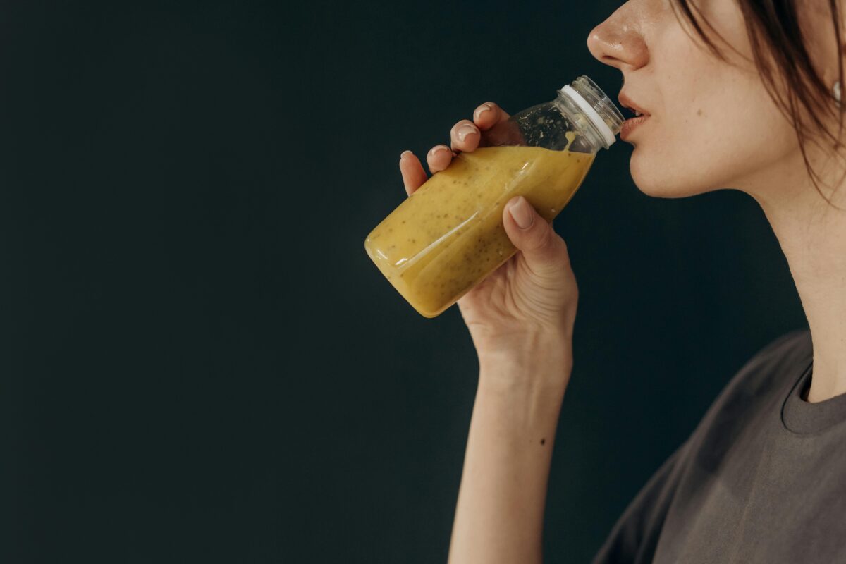 Osoba pije zdravý smoothie nápoj z fľaše. Zamerané na akt zdravého životného štýlu.