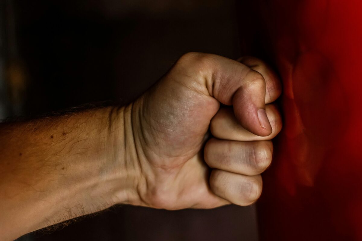 Ľudská ruka zovretá v päsť smerujúca k červenému povrchu, detailný pohľad.