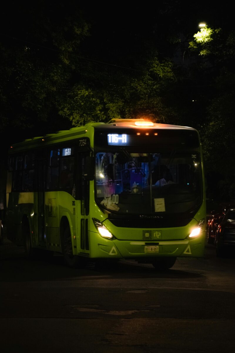 Zelený autobus na nočnej ulici, s číslicou 116-A na čelnej tabuli, osvetlený pouličnou lampou.