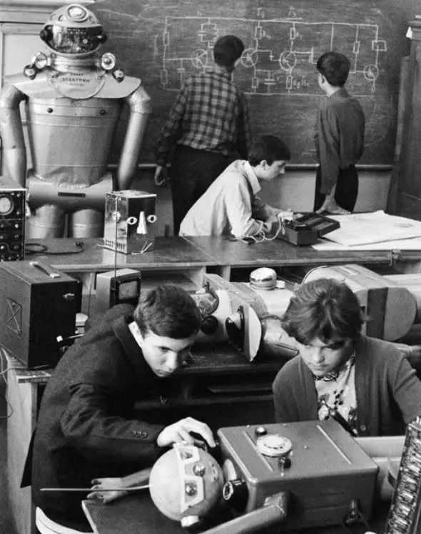 Študenti v laboratóriu robota, diskutujúci o technickom návrhu na tabuli. Retrospektívna scéna vzdelávania v robotike.